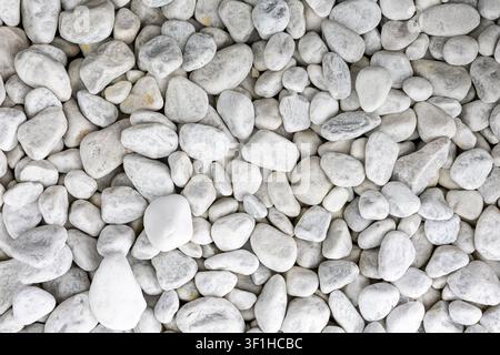 Smooth White and Gray Pebbles Natural Stone Background. Overhead close-up of smooth white and gray pebbles forming a natural stone texture with varied Stock Photo