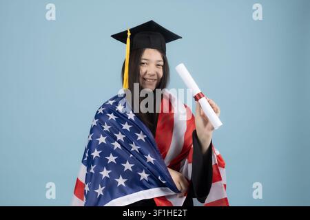 Proud female graduate holding diploma scroll and american flag Stock Photo
