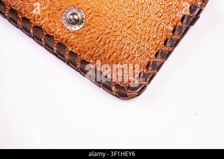 Close-up textured leather wallet corner, intricate stitching, metallic rivet, rich brown tone, subtle embossed pattern, dark brown thread contrast, pr Stock Photo