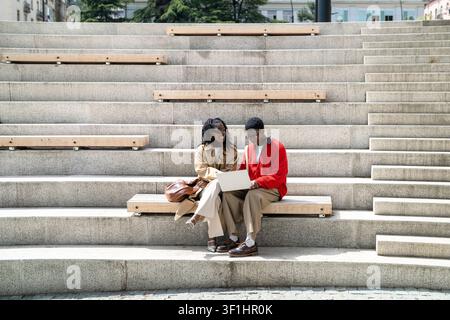 Positive smiling african american students friends man and woman on daily break relaxing outdoors. Stock Photo