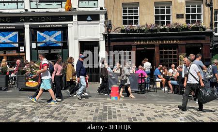 People enjoying an al fresco refreshment in the sunny weather at the Filling Station and Merchants Tavern on a busy Royal Mile, Edinburgh Scotland Stock Photo