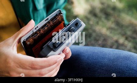 Person inserting cassette tape into portable player outdoors - Retro audio and nostalgia lifestyle trend Stock Photo