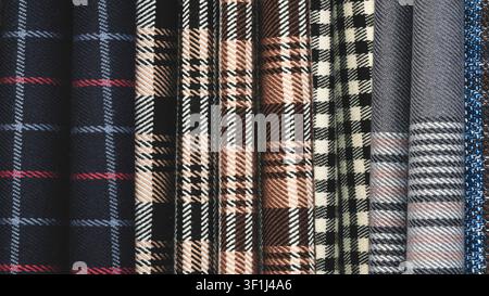 Close-up of various plaid fabric swatches. Colors range from deep blue to red and beige. Patterns include houndstooth, check, and striped designs. Tex Stock Photo