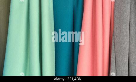 Close-up of fabric swatches in mint green, teal, peach, and gray. Ribbed texture visible in each sample. Soft folds highlight smooth surfaces. Ideal f Stock Photo
