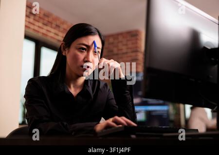 Tired tech engineer brainstorming ideas about coding solution, finding algorithm to create database script, feeling pensive and thinking about software developing system in it agency. Stock Photo