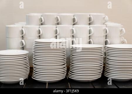 Stacked white plates and cups arranged neatly, emphasizing clean organization and catering setup Stock Photo