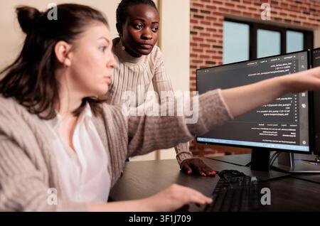 Diverse programmers writing HTML script on terminal window at an IT office desk, using screens, scripts and cloud computing tools for software engineering workflow. Stock Photo