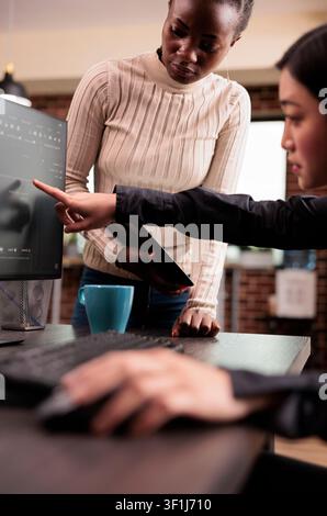 Team of software developers discussing source code at an IT office desk, using screens, scripts and cloud computing tools for software engineering workflow. Stock Photo
