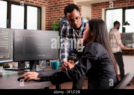 Database administrators debug an algorithm in a software office, reviewing source code and solving development errors as a team, connecting paperwork, planning and professional workflow. Stock Photo