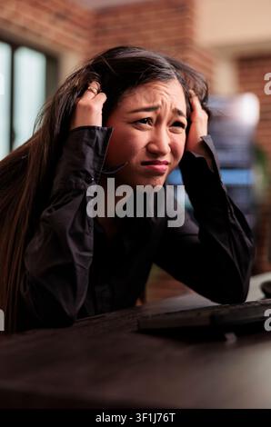 Exhausted programmer sits at a desk writing artificial intelligence code, feeling the pressure of software development workload in an IT company office. Stock Photo