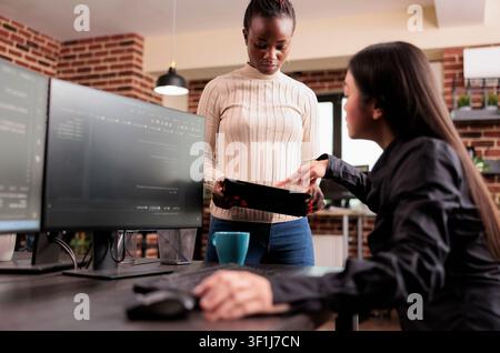 Team of software developers debugging algorithm working in it developing agency, Programming engineers analyzing source code on computer monitor, comparing data script in busy agency office. Stock Photo