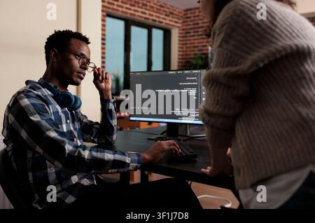 Software developers sitting at desk and developing a functional data encryption system, Multiethnic cyber security team members in agency office writing cloud database processing algorithm. Stock Photo