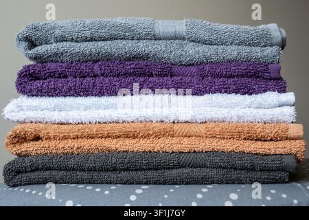 Close-up of a neat stack of clean colorful cotton towels on an ironing board, domestic laundry and home textile concept. Stock Photo