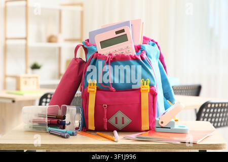 Colorful school backpack with books and calculator on a wooden desk, ready for back to school season Stock Photo