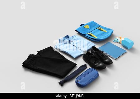 School uniform with blue shirt, black trousers, shoes, backpack, and stationery for back to school preparation Stock Photo