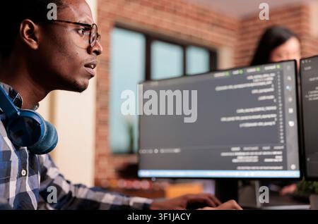 System engineer typing machine learning server code on computer, sitting at desk in software company. Programming engineer working on database system with coding script in it security agency. Stock Photo