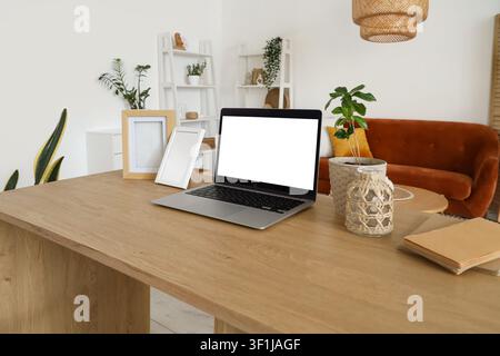 Blank laptop with frames on programmers desk in living room Stock Photo