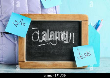 Arabic language learning with a small chalkboard displaying "العربية" and sticky notes with vocabulary words, School supplies including pens and penci Stock Photo
