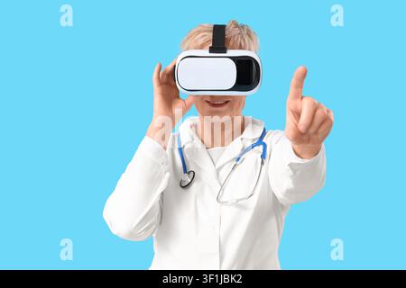 Mature female doctor in VR glasses using virtual screen on blue background Stock Photo