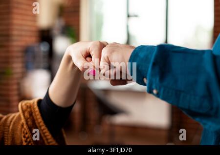 Business professionals share fist bump in office, emphasizing Christmas celebration, pet companionship and family warmth in a professional startup setting. Stock Photo