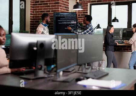 Cybersecurity engineers review code and encryption processes to secure mainframe data systems using blockchain technology in a focused tech office. Stock Photo