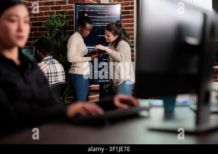 Software engineers discuss a cloud storage problem while reviewing code, database performance and artificial intelligence ideas in a programming office. Stock Photo