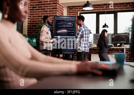 Two programming engineers examine HTML code on a large screen, checking errors in an artificial intelligence project for a technology company. Stock Photo