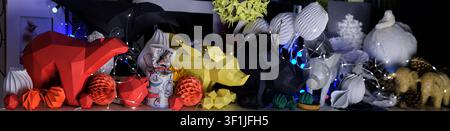 A collection of colorful low poly geometric paper sculptures depicting various animals displayed on a shelf with warm festive string lighting. Stock Photo