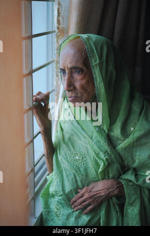 Elderly woman gazing out the window during daytime Stock Photo