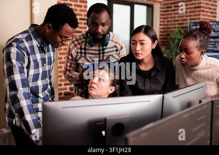 Diverse system engineers analyze HTML script and source code on a computer, compiling application logic in an IT data agency, with code review and debugging context. Stock Photo