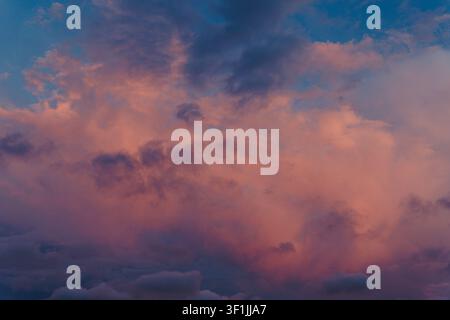 Dramatic sunset sky filled with billowing pink and blue clouds, creating a soft, colorful, and atmospheric natural backdrop Stock Photo