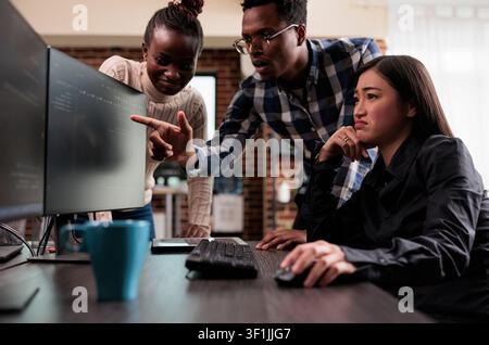 Team leader pointing out technical anomalies with programmers, screens and infrastructure details supporting software development and system monitoring. Stock Photo