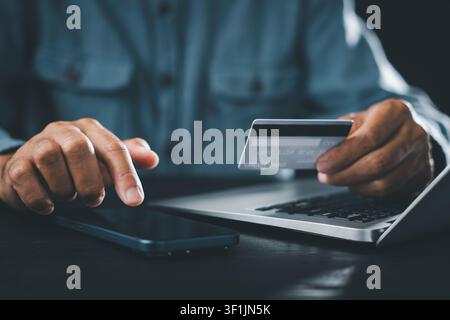 Paying, shopping, credit, card, mobile, phone, computer, home, business, concept shown by hands of man holding plastic card and touching screen of sma Stock Photo
