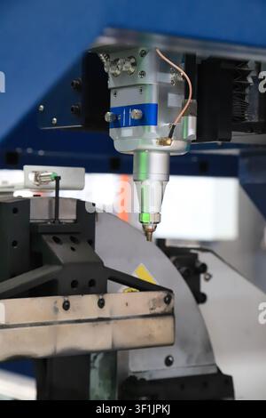 A detailed close-up shot of a laser cutting nozzle, a key component of a high-power fiber laser cutting machine. The silver and blue industrial tool i Stock Photo