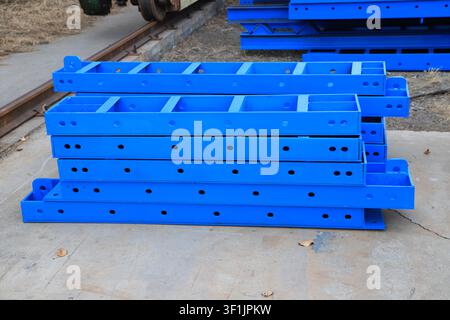 The image shows neatly stacked blue curved steel formwork in a factory area. The metal plates are covered with connecting holes and lifting lugs, whic Stock Photo