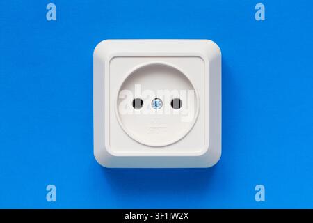 European electrical outlet on a blue background. Close-up of a white electrical outlet. Stock Photo