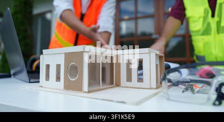 Architectural house model on table with engineers collaborating in background Stock Photo