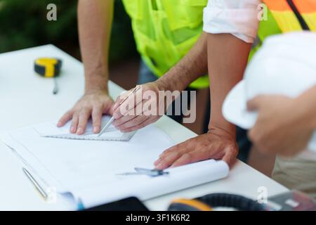 Cropped hands of architects drafting blueprint with ruler for construction project Stock Photo