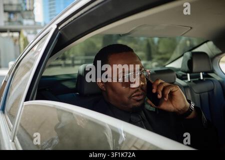 Black Businessman Talking on Smartphone in Car during Commute Stock Photo