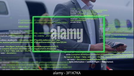 Male exec manipulating phone at jet ramp, verifying flight data via green UI code Stock Photo