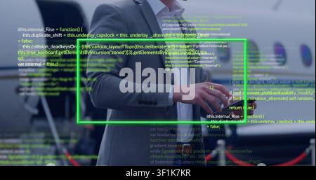 Male exec manipulating phone at jet ramp, verifying flight data via green UI code Stock Photo