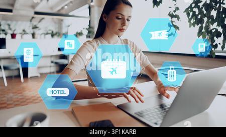 Travel planning takes place in a city office with a woman using a laptop for booking flights and hotels Stock Photo