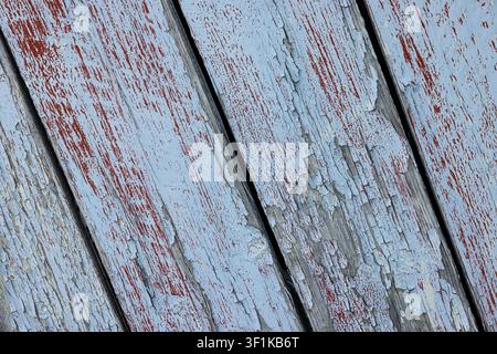 Weathered wood planks show faded red and gray paint. Peeling layers reveal rustic, aged texture. Cracks and scratches hint at time's passage. Perfect Stock Photo