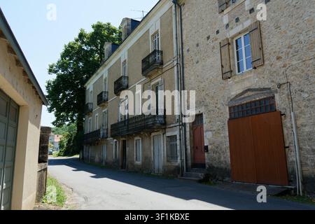 Cubjac village street showing old stone buildings, closed shutters, and wrought iron balconies Stock Photo