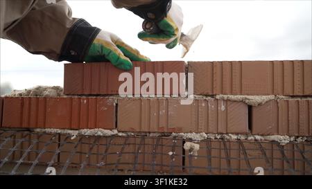 Construction worker carefully placing bricks, building a new wall using mortar and a trowel Stock Photo