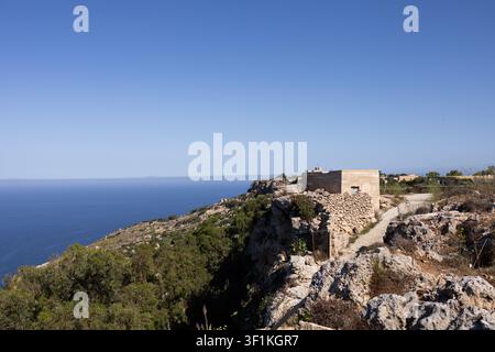 Old stone building on a rocky cliff edge with a scenic view of the mediterranean sea. Stock Photo