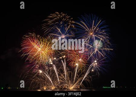 Colorful fireworks display featuring gold red and blue pyrotechnics exploding against a dark night sky during a festive celebration. Stock Photo