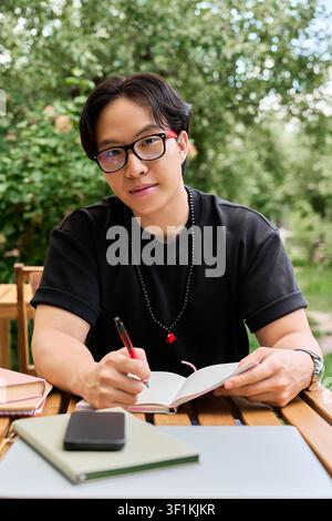 Young asian man immersed in work, capturing ideas on a notepad Stock Photo