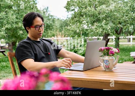 Freelancer enjoys remote work surrounded by greenery and colorful flowers outdoors Stock Photo