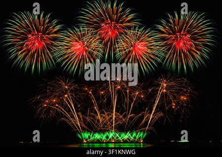 Bright rhythmic firework explosions illuminate the darkness during a professional celebration event. Stock Photo